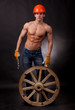 Muscular young man with a wagon wheel on a black background.