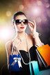 Beauty  young woman in sunglasses carrying colored shopping bag