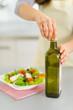 Photo: Closeup on woman opening bootle of olive oil to add into salad Closeup on woman opening bootle of olive oil to add into salad