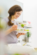 Smiling young woman eating salad and talking mobile phone