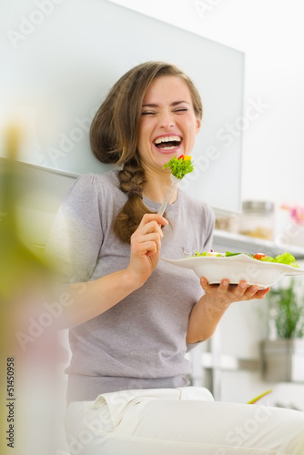 Photo: Smiling young woman eating salad and talking mobile phone Smiling young woman eating salad and talking mobile phone