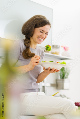 Photo: Smiling young woman eating salad and talking mobile phone Smiling young woman eating salad and talking mobile phone