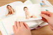 Photos in hands and photo album on wooden table