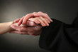 Priest holding woman hand, on black background