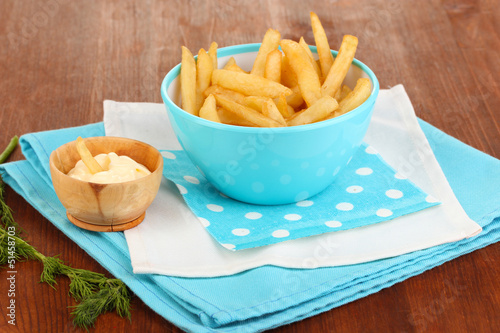 Photo: French fries in bowl on wooden table close-up French fries in bowl on wooden table close-up