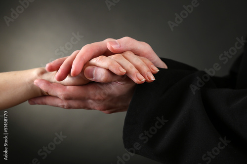 Photo: Priest holding woman hand, on black background Priest holding woman hand, on black background