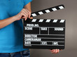 Movie production clapper board in hands on grey background