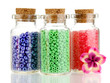 Little bottles full with colorful beads isolated on white