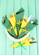 Forks and knives wrapped in green and yellow paper napkins,