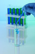 Identical test tubes and hand on blue background