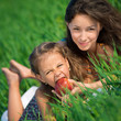 Photo: Happy girls on green grass with apple Happy girls on green grass with apple