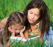 Happy girls reading book on green grass