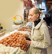 Young woman choosing fresh eggs on market