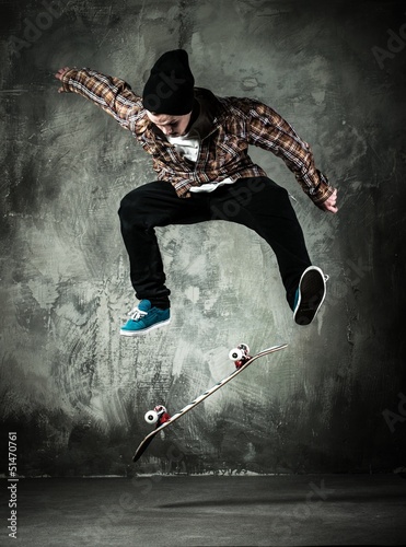 Photo: Young man in hat and shirt performing stunt on skateboard Young man in hat and shirt performing stunt on skateboard