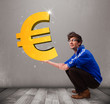 Good-looking boy holding a big 3d gold euro sign