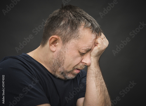 Photo: Headache. Man with face closed by hand Headache. Man with face closed by hand