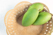 green mangoes in a plastic wooden basket on white background