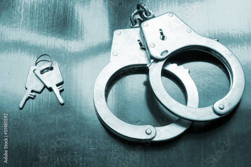 Photo: Steel metallic handcuffs with keys on wooden table Steel metallic handcuffs with keys on wooden table