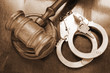 Gavel and handcuffs on wooden background