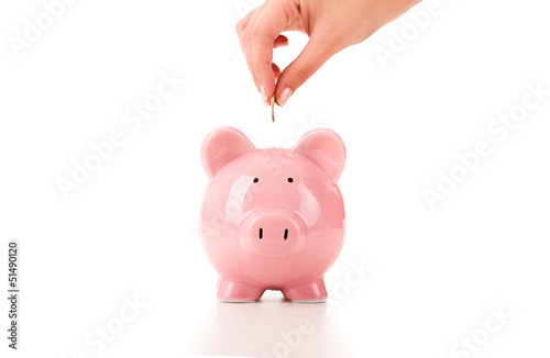 Photo: Female hand putting a coin into piggy bank Female hand putting a coin into piggy bank