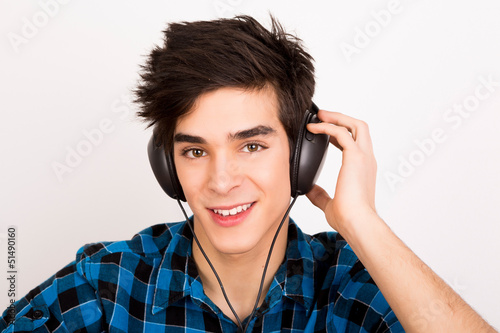 Photo: Young man listening music with headphones at home Young man listening music with headphones at home