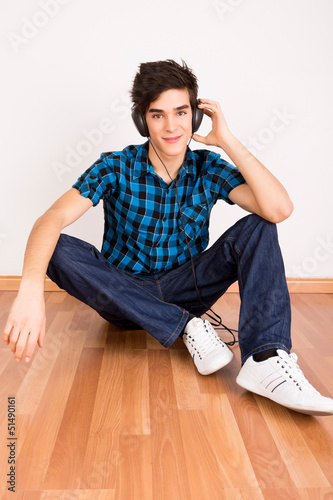 Photo: Young man listening music with headphones at home Young man listening music with headphones at home