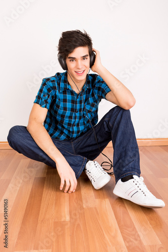 Photo: Young man listening music with headphones at home Young man listening music with headphones at home