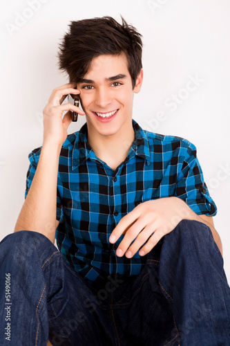 Photo: Young man talking on the phone at home Young man talking on the phone at home