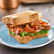 Foto: BLT bacon lettuce tomato sandwich with toast off to the side. BLT bacon lettuce tomato sandwich with toast off to the side.