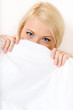 Girl in bed covers her face with white eiderdown