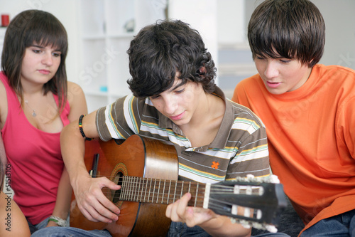 Photo: Teens listening to their peer play the guitar Teens listening to their peer play the guitar