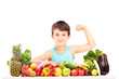 Healthy child showing his arm muscles and sitting on a table ful