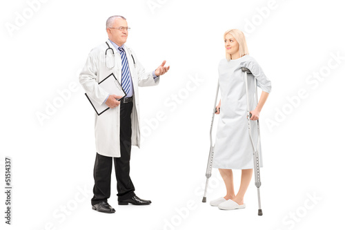 Photo: Blond female patient in hospital gown with crutches and medical Blond female patient in hospital gown with crutches and medical