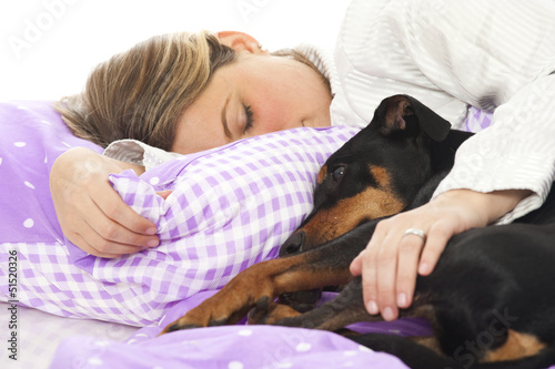 Photo: Young woman lying in bed with dog Young woman lying in bed with dog