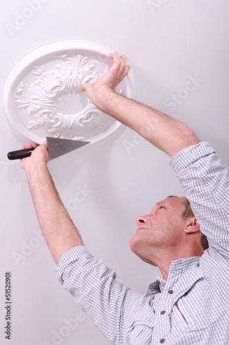 Photo: Decorator affixing a ceiling rose Decorator affixing a ceiling rose