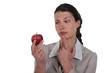 Photo: woman holding an apple and thinking woman holding an apple and thinking