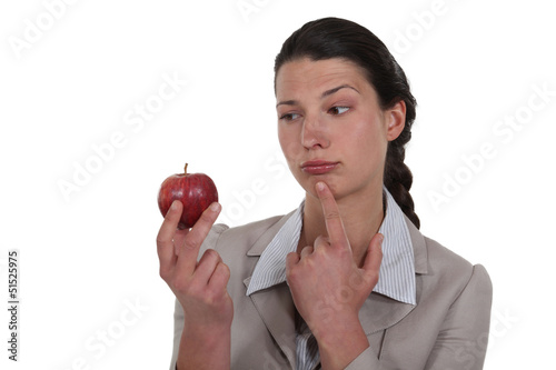 Photo: woman holding an apple and thinking woman holding an apple and thinking