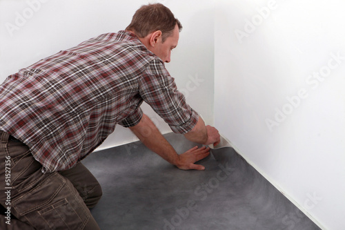 Photo: Man laying new carpet in room Man laying new carpet in room
