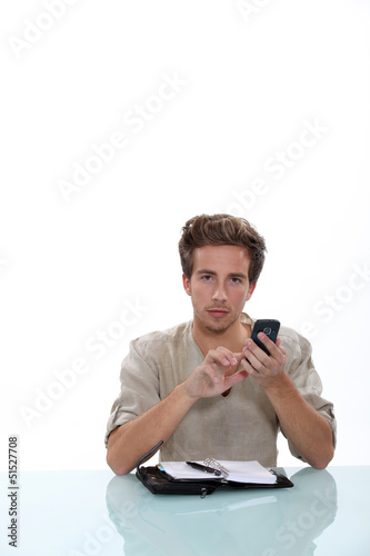 Photo: Man sitting a desk with a cellphone and personal organizer Man sitting a desk with a cellphone and personal organizer