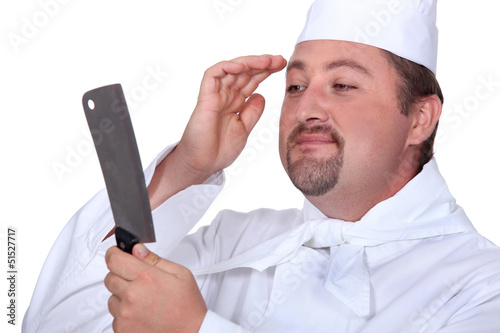 Photo: Chef looking at his reflection in a knife Chef looking at his reflection in a knife