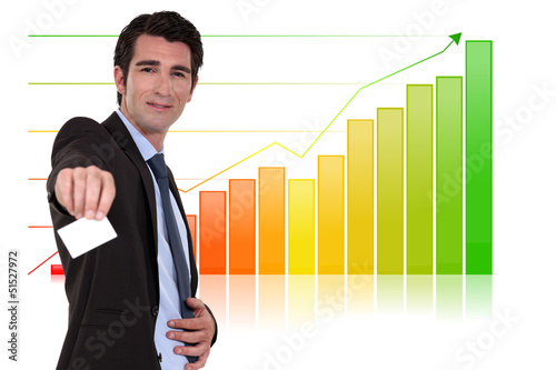 Photo: Businessman with calling card standing by bar chart Businessman with calling card standing by bar chart
