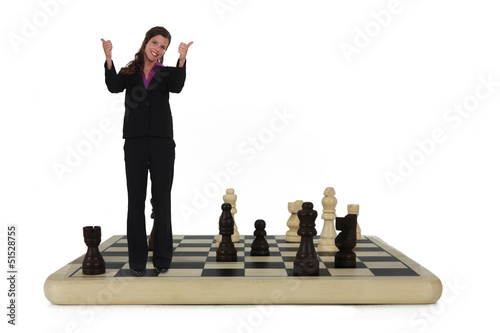 Photo: Businesswoman standing on chess board Businesswoman standing on chess board