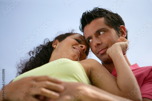Photo: Low-angle view of couple stood hugging outdoors Low-angle view of couple stood hugging outdoors