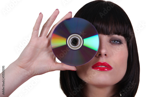 Photo: Woman holding a cd to an her eye Woman holding a cd to an her eye