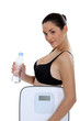 Brunette holding bottle of water and scales