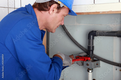 Photo: Plumber tightening a joint with a wrench Plumber tightening a joint with a wrench