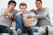 Photo: Three male friends watching television together Three male friends watching television together