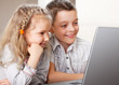 Happy kids playing laptop at home