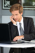 Young contractor with laptop and cell phone