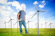 Student with a light bulb head in middle of wind turbine field